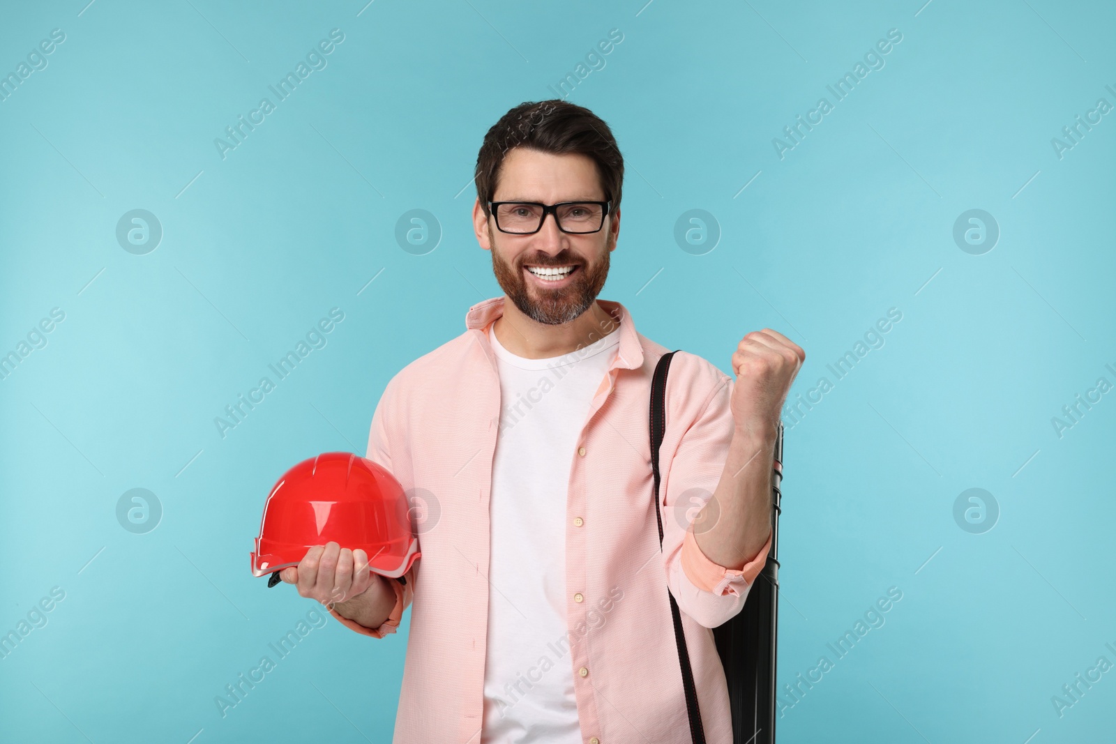 Photo of Architect with drawing tube and hard hat on light blue background