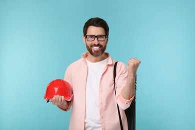 Architect with drawing tube and hard hat on light blue background