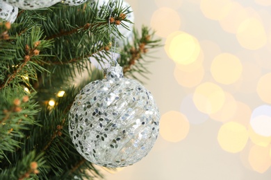 Photo of Holiday bauble hanging on Christmas tree against blurred lights, closeup. Space for text