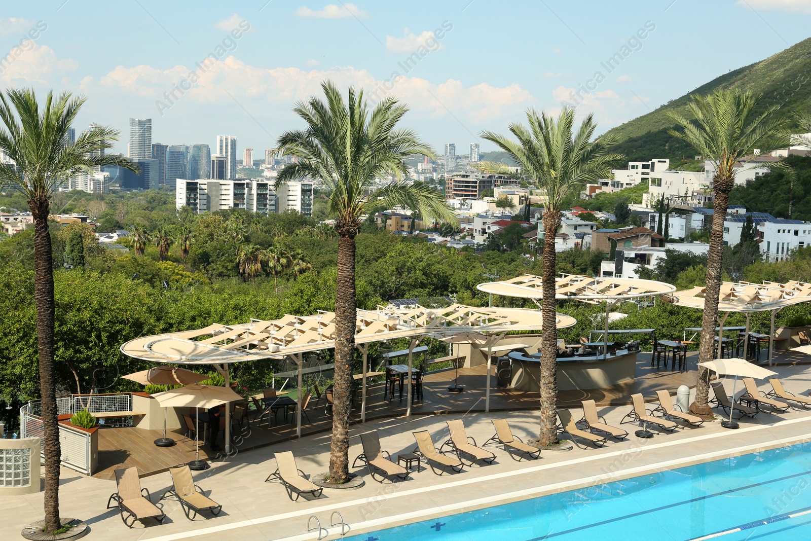 Photo of Sunbeds and palm trees near outdoor swimming pool