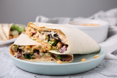 Delicious hummus wraps with vegetables on light grey textured table