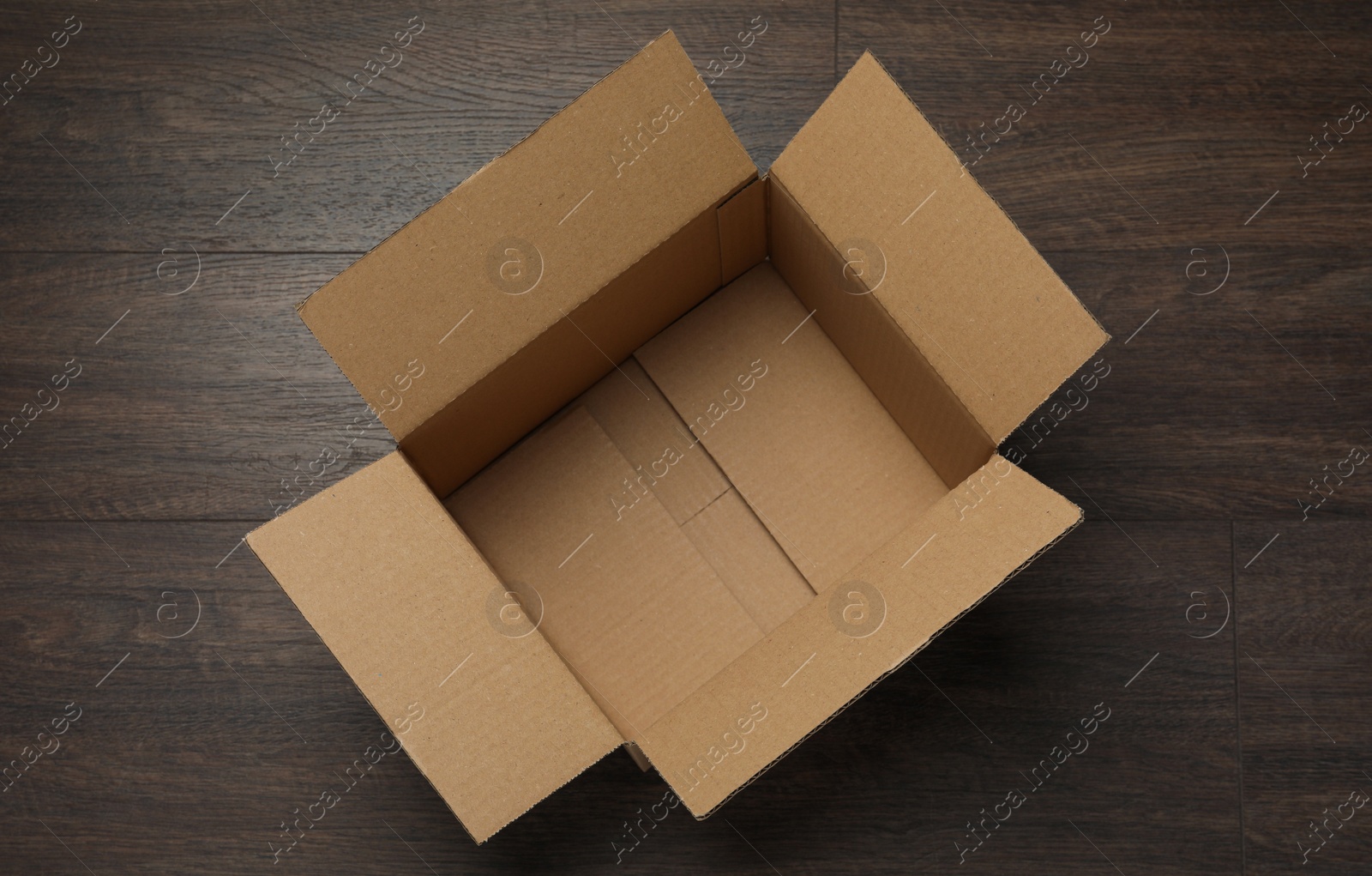 Photo of Empty open cardboard box on wooden table, top view