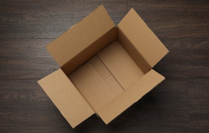 Photo of Empty open cardboard box on wooden table, top view