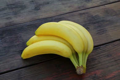 Photo of Bunch of ripe yellow bananas on wooden table