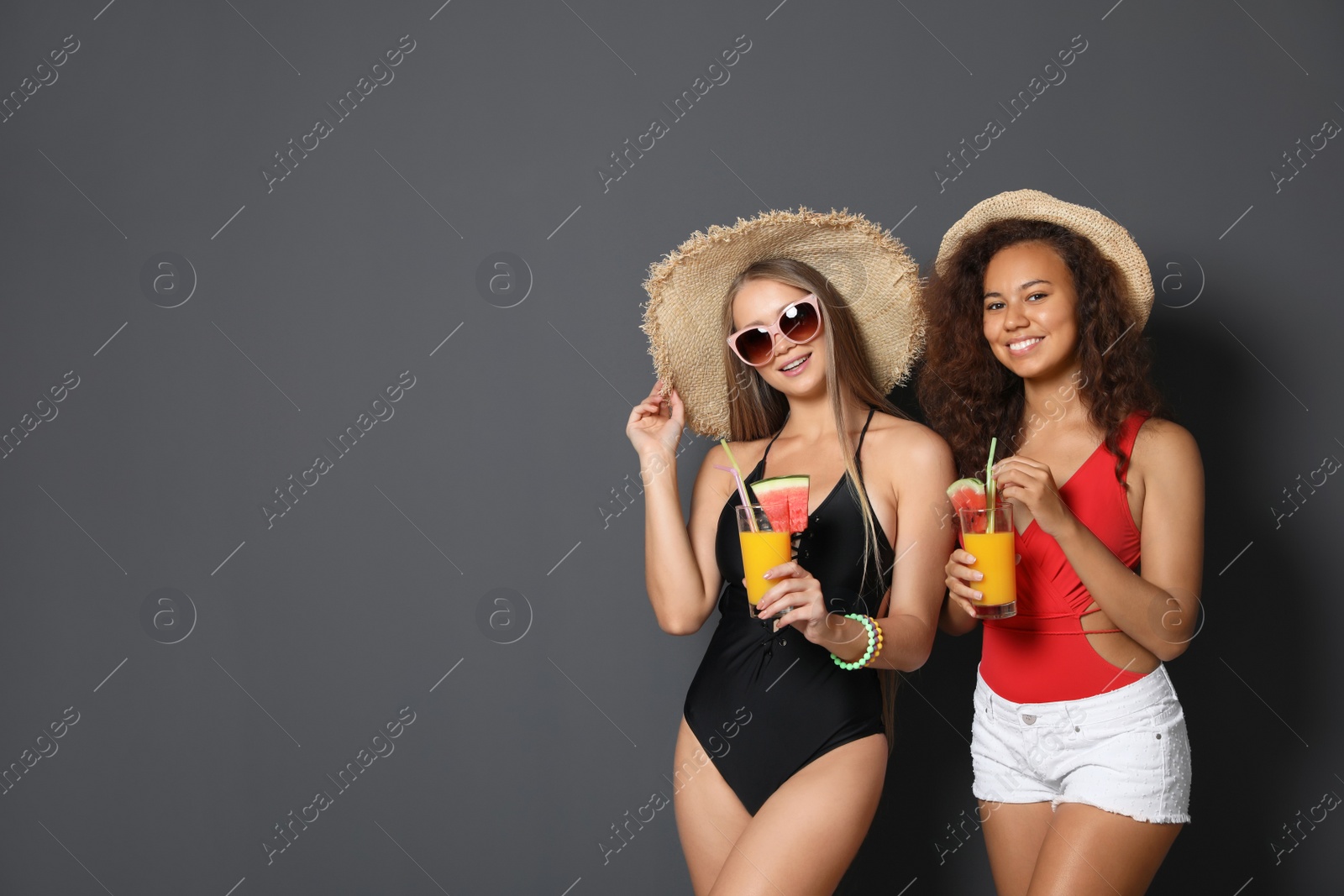 Photo of Beautiful young women in beachwear with cocktails on dark background. Space for text