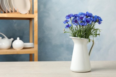 Photo of Bouquet of beautiful cornflowers in vase on white wooden table at home. Space for text
