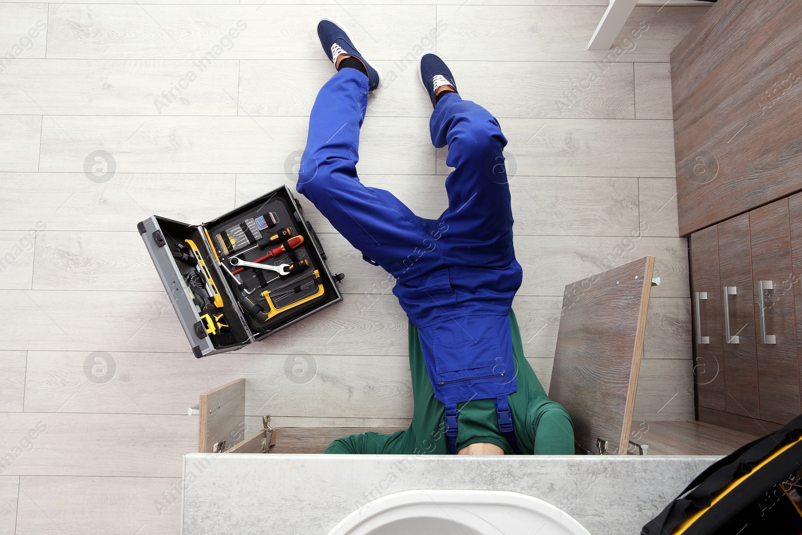 Photo of Male plumber repairing kitchen sink, top view