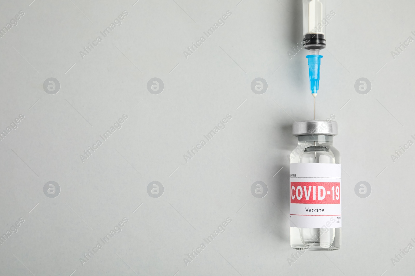 Photo of Filling syringe with coronavirus vaccine on light background, flat lay. Space for text