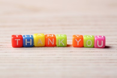 Photo of Phrase Thank You made of colorful cubes on light wooden table