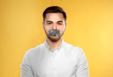 Man with taped mouth on yellow background. Speech censorship