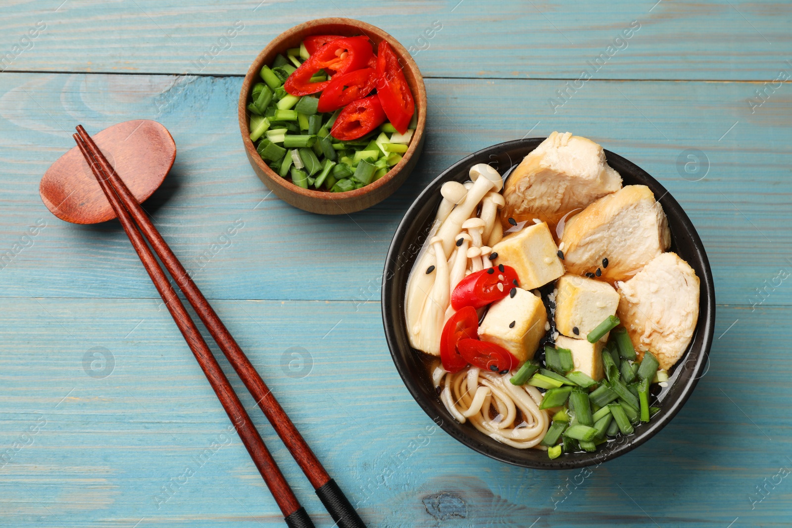 Photo of Delicious ramen served on light blue wooden table, flat lay. Noodle soup