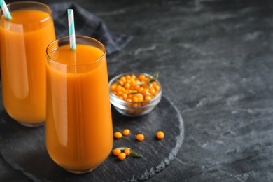 Photo of Delicious sea buckthorn juice and fresh berries on black table. Space for text