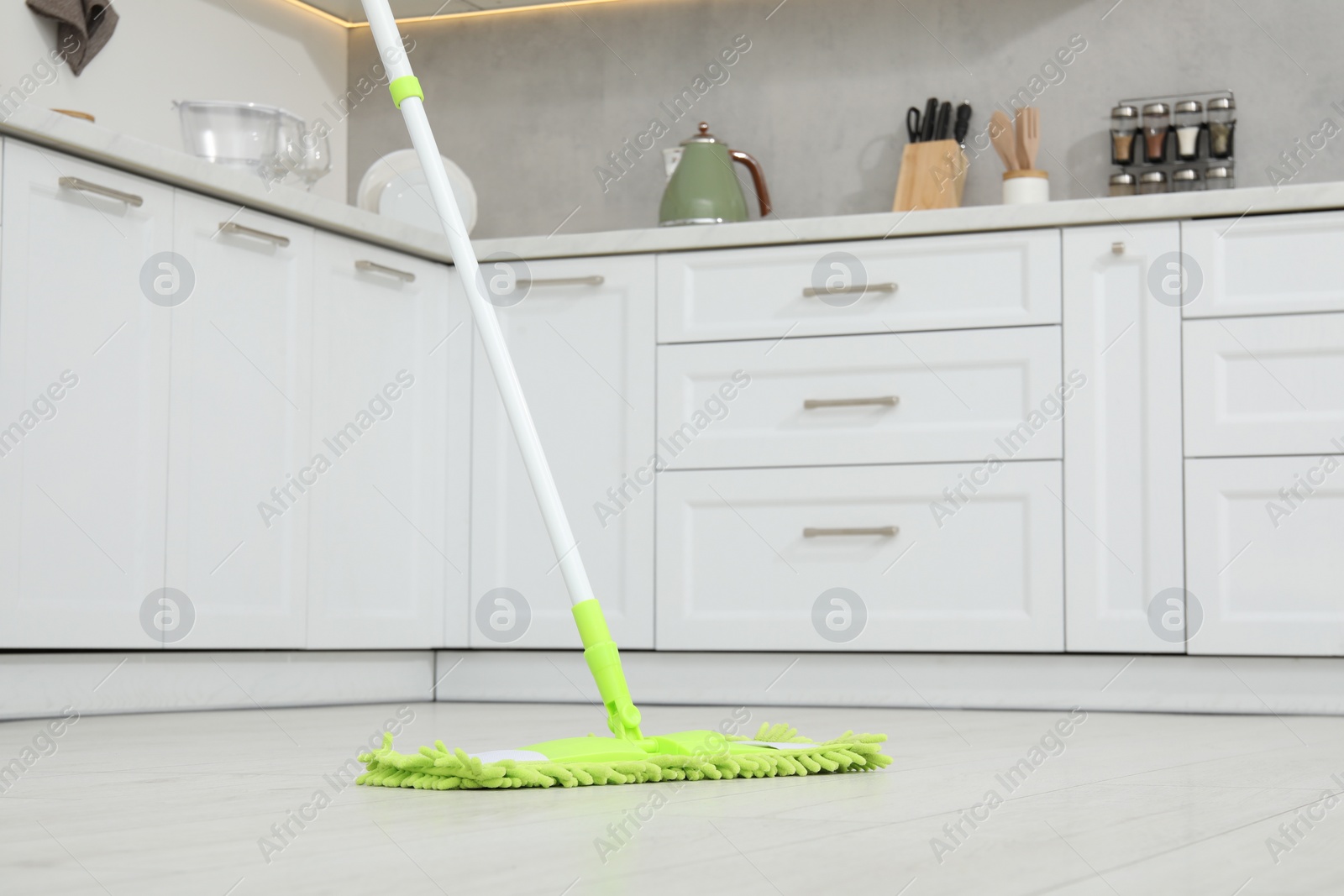 Photo of Cleaning of parquet floor with mop in kitchen, low angle view