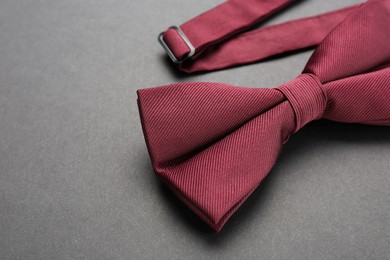 Stylish burgundy bow tie on dark background, closeup. Space for text