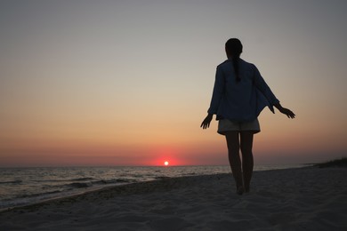 Girl near sea at sunset, back view