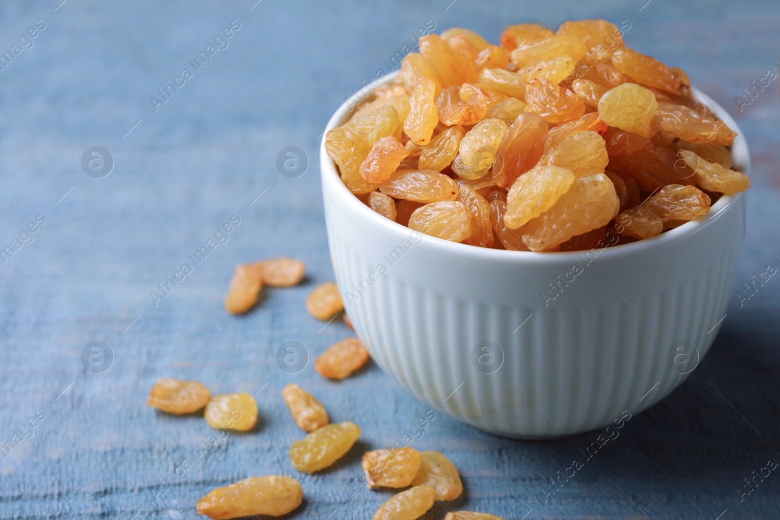 Photo of Bowl with raisins on wooden table, space for text. Dried fruit as healthy snack