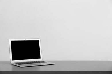 Photo of Modern laptop with blank screen on table against light background