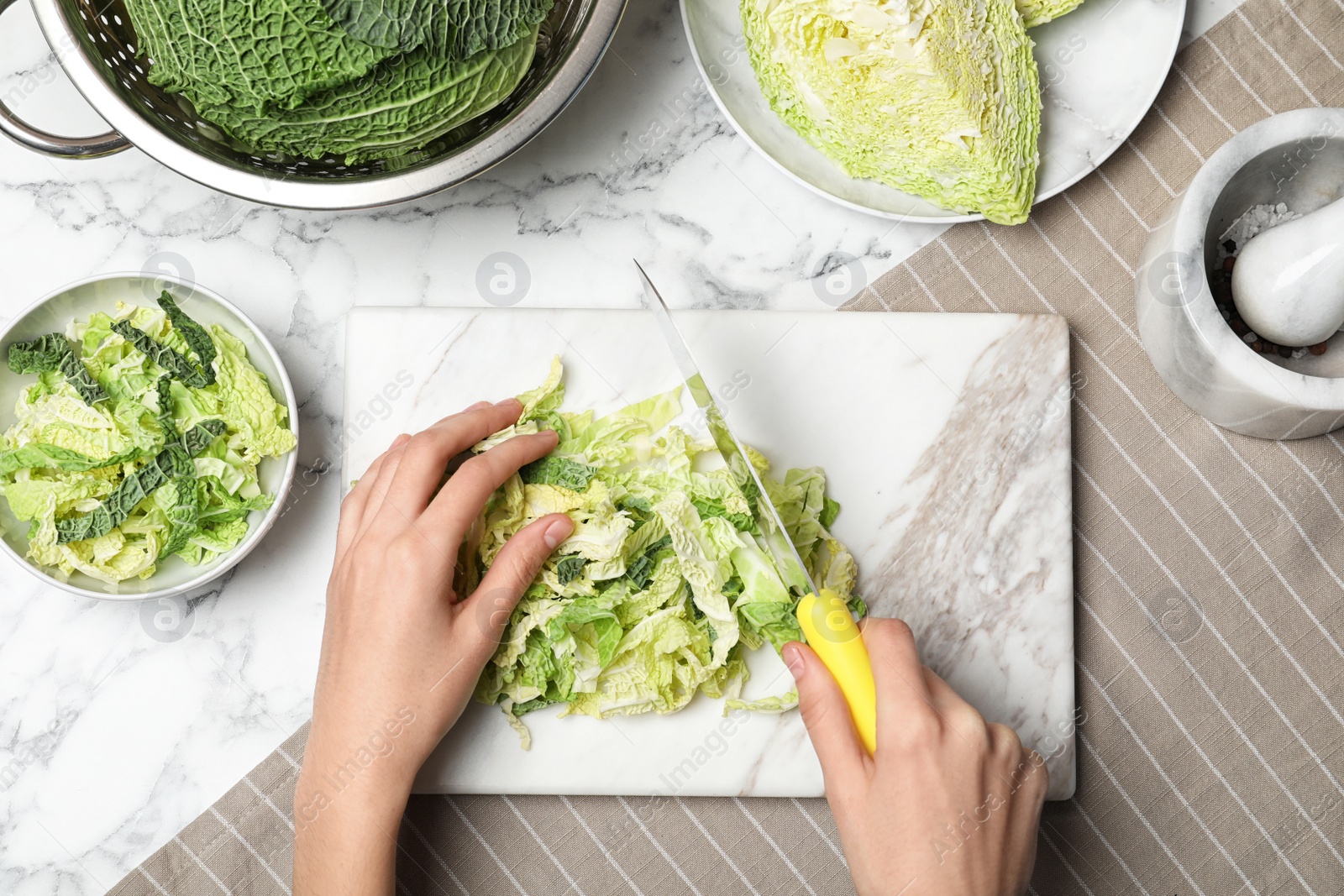 Photo of Woman cutting savoy cabbage on marble board at table, top view