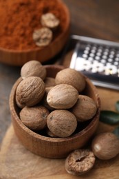 Photo of Whole nutmegs in wooden bowl on table