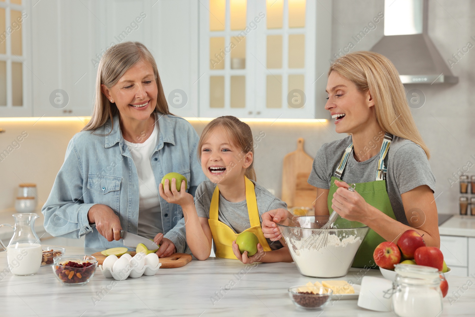 Photo of Three generations. Happy grandmother, her daughter and granddaughter cooking together in kitchen