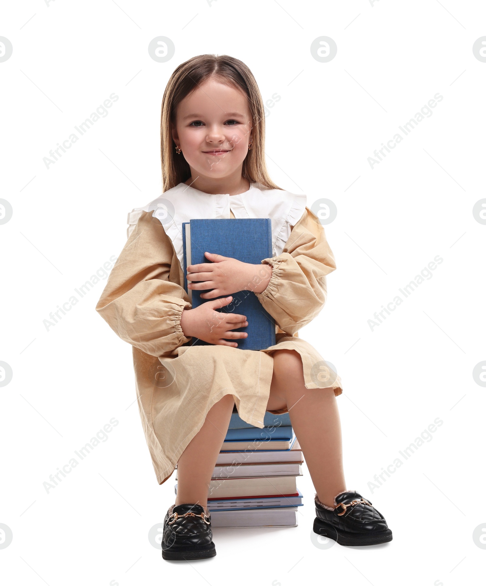 Photo of Cute little girl sitting on stack of books against white background