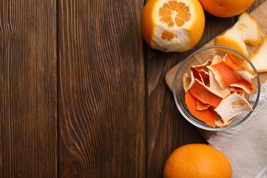 Photo of Dry peels and oranges on wooden table, flat lay. Space for text