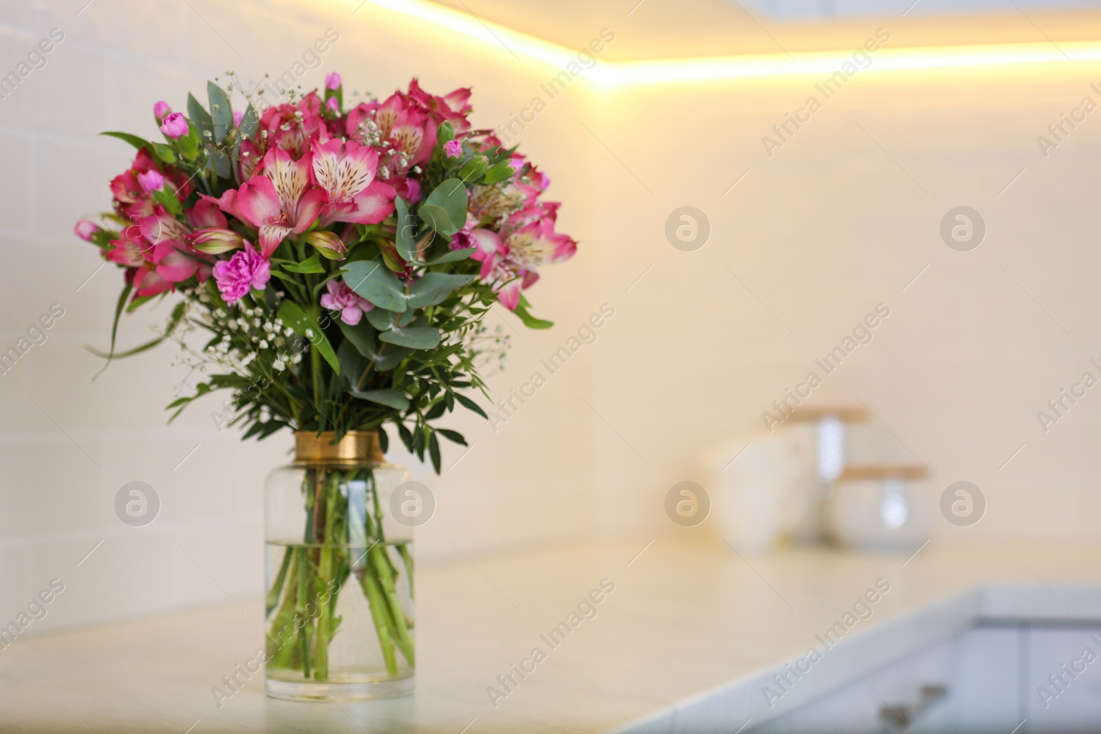 Photo of Vase with beautiful alstroemeria on countertop in kitchen, space for text. Interior design