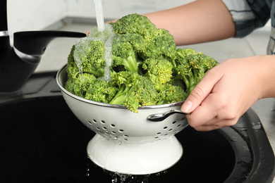 Photo of Woman washing fresh green broccoli in kitchen sink, closeup