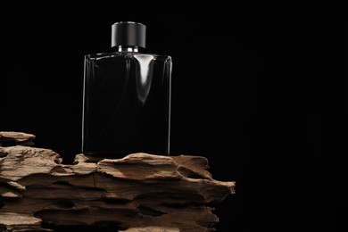 Luxury men`s perfume in bottle against black background. Space for text