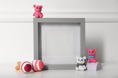 Photo of Empty photo frame and cute toys near wall, space for text. Baby room interior element