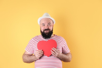 Emotional man with paper heart on color background