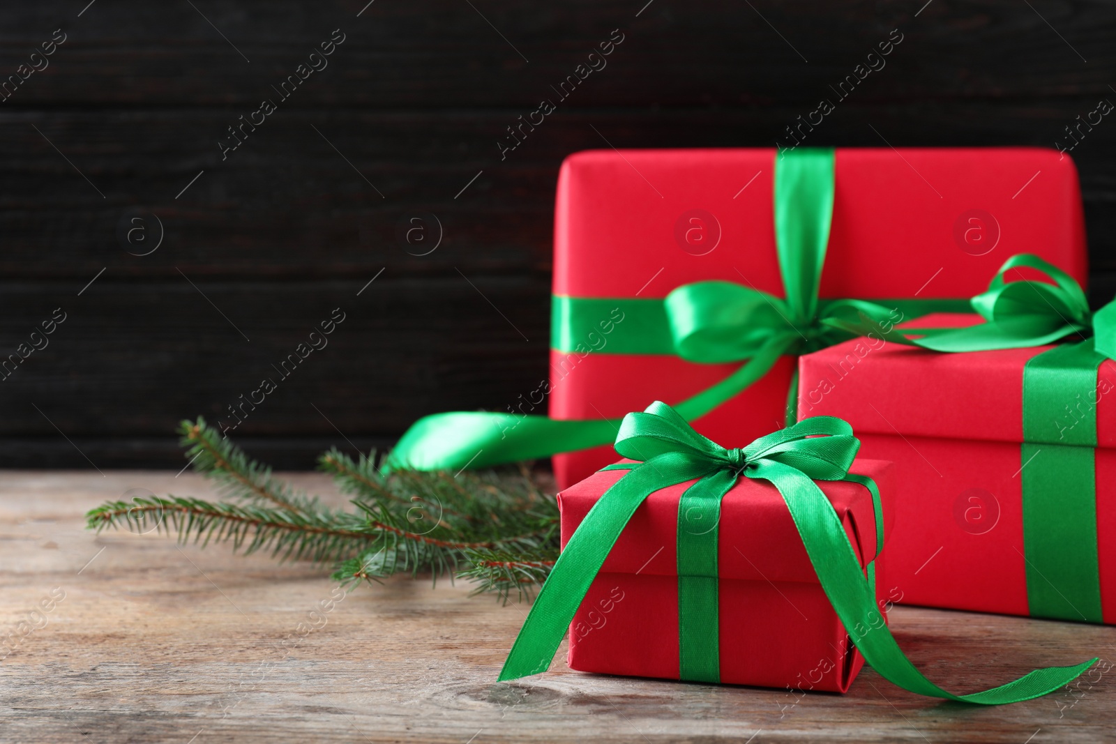 Photo of Christmas gifts on wooden table against dark background. Space for text