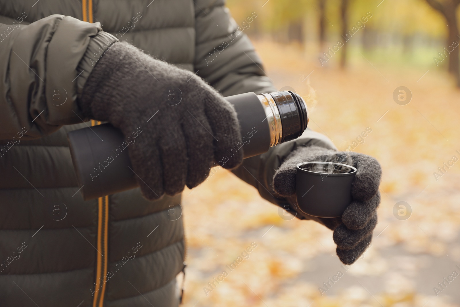 Photo of Man pouring drink from thermos into cap outdoors, closeup