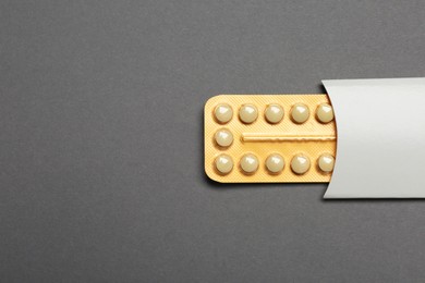 Birth control pills on grey background, top view. Space for text