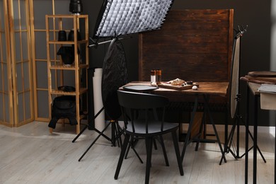 Photo of Professional equipment and composition with delicious meat medallions on wooden table in studio. Food photography