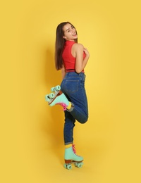 Young woman with roller skates on color background