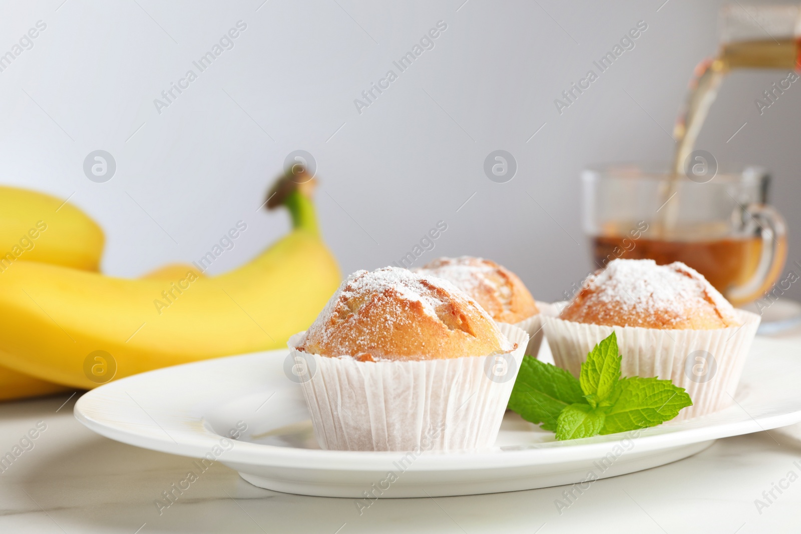 Photo of Tasty muffins served with mint on white table, closeup