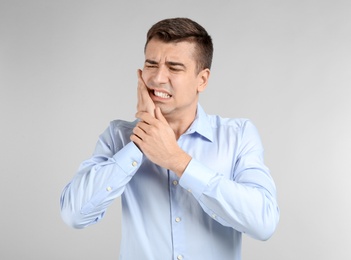 Photo of Young man suffering from toothache on light background