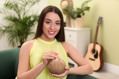 Young woman with fresh coconut at home. Exotic fruit