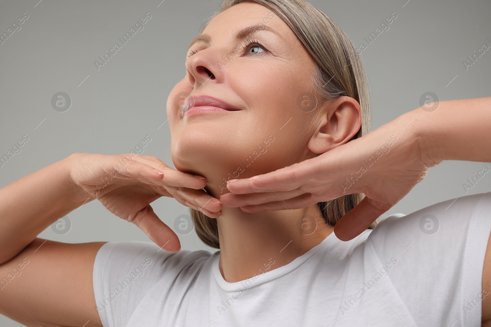 Photo of Beautiful woman touching her neck on grey background, low angle view