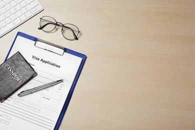 Photo of Visa application form, passport, glasses and pen on wooden table, flat lay. Space for text