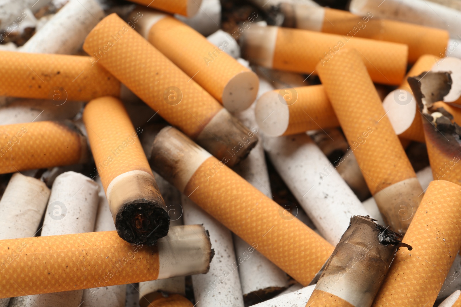 Photo of Pile of cigarette stubs as background, closeup view