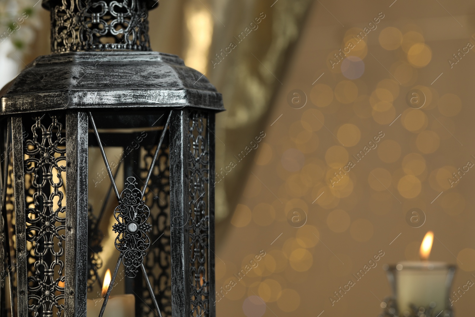 Photo of Arabic lantern and burning candles against blurred lights, space for text