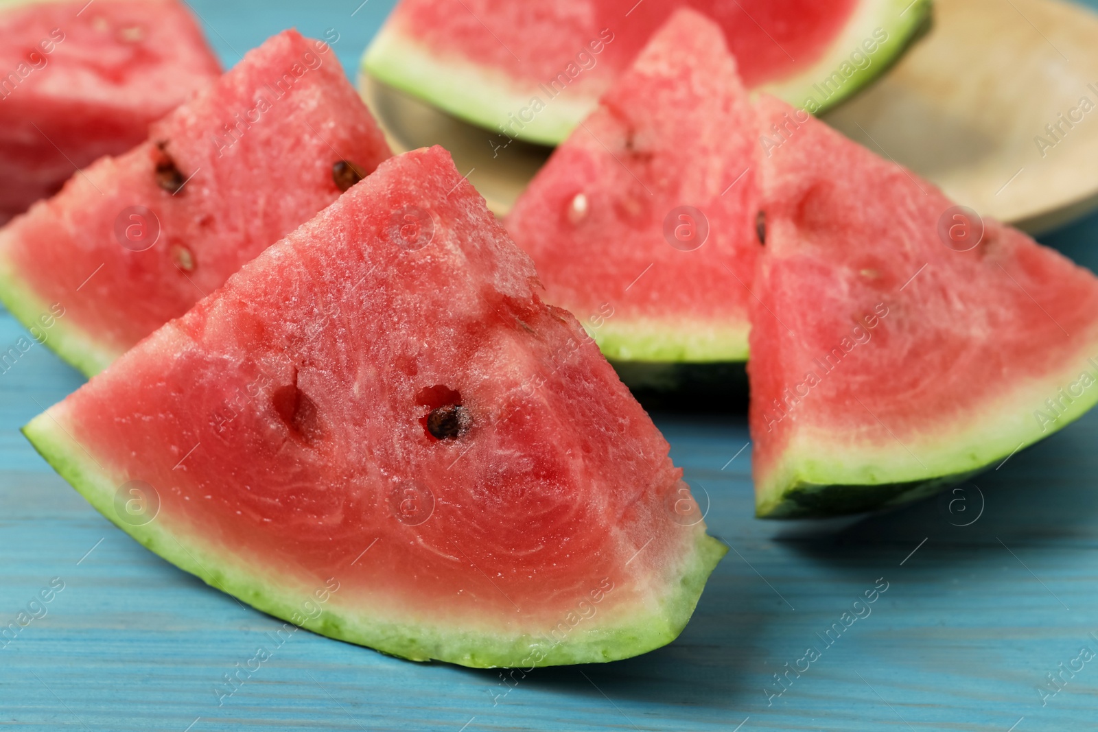 Photo of Slices of tasty ripe watermelon on turquoise wooden table, closeup