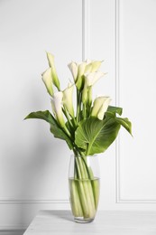 Photo of Beautiful calla lily flowers in vase on table