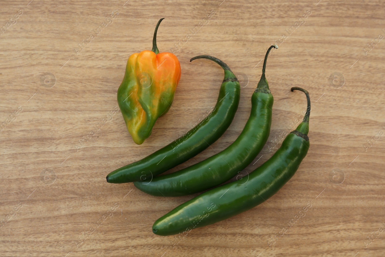 Photo of Different fresh ripe peppers on wooden table, flat lay