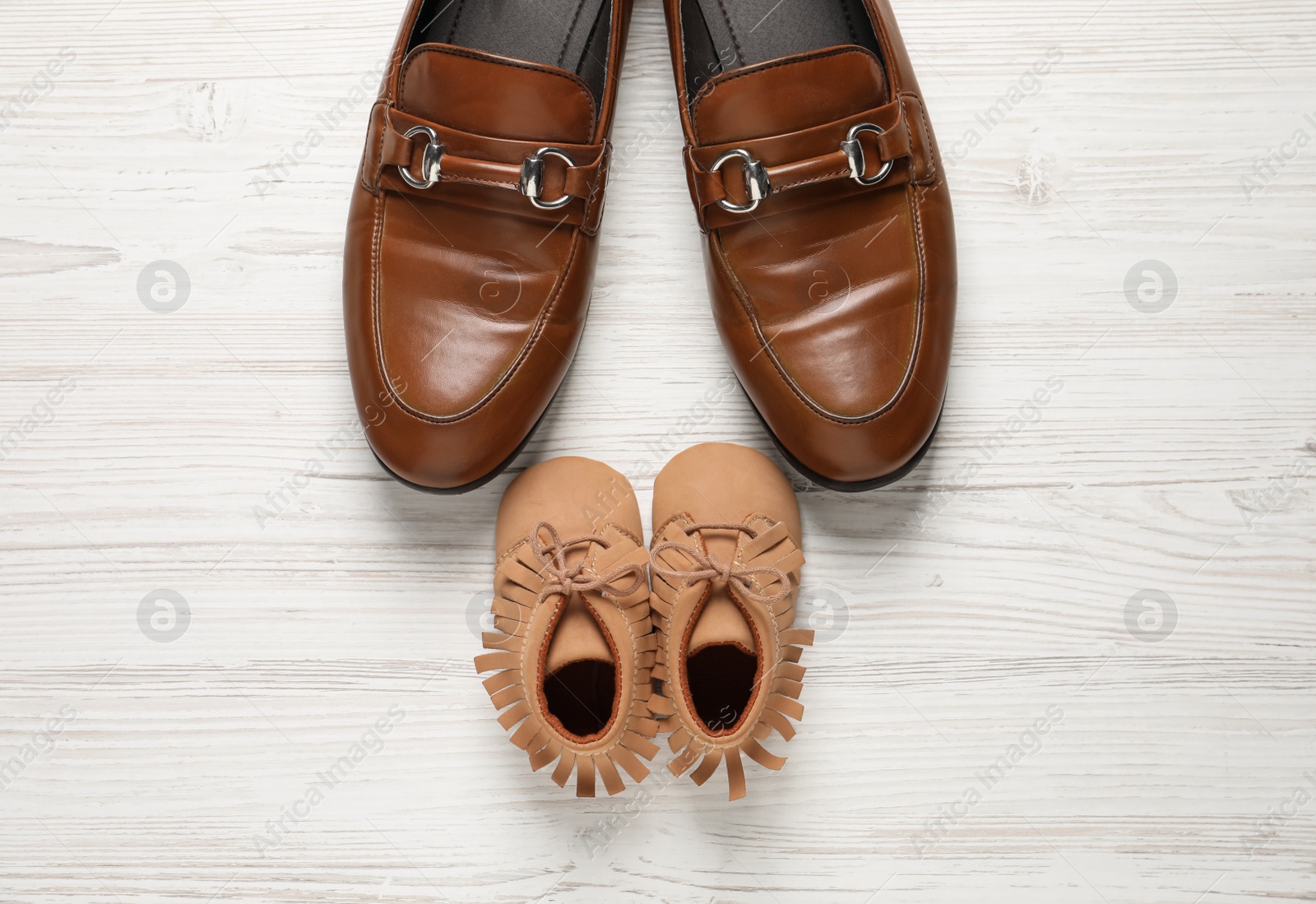 Photo of Happy Father's Day. Shoes for dad and child on white wooden background, flat lay