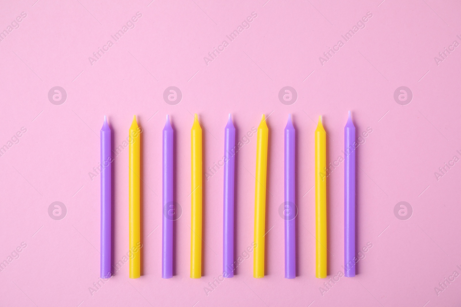 Photo of Colorful birthday candles on pink background, flat lay