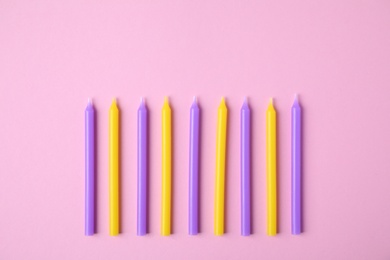 Colorful birthday candles on pink background, flat lay