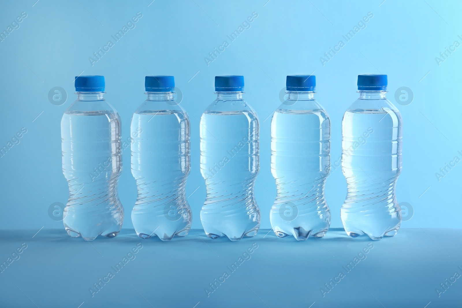 Photo of Row of plastic bottles with water on color background